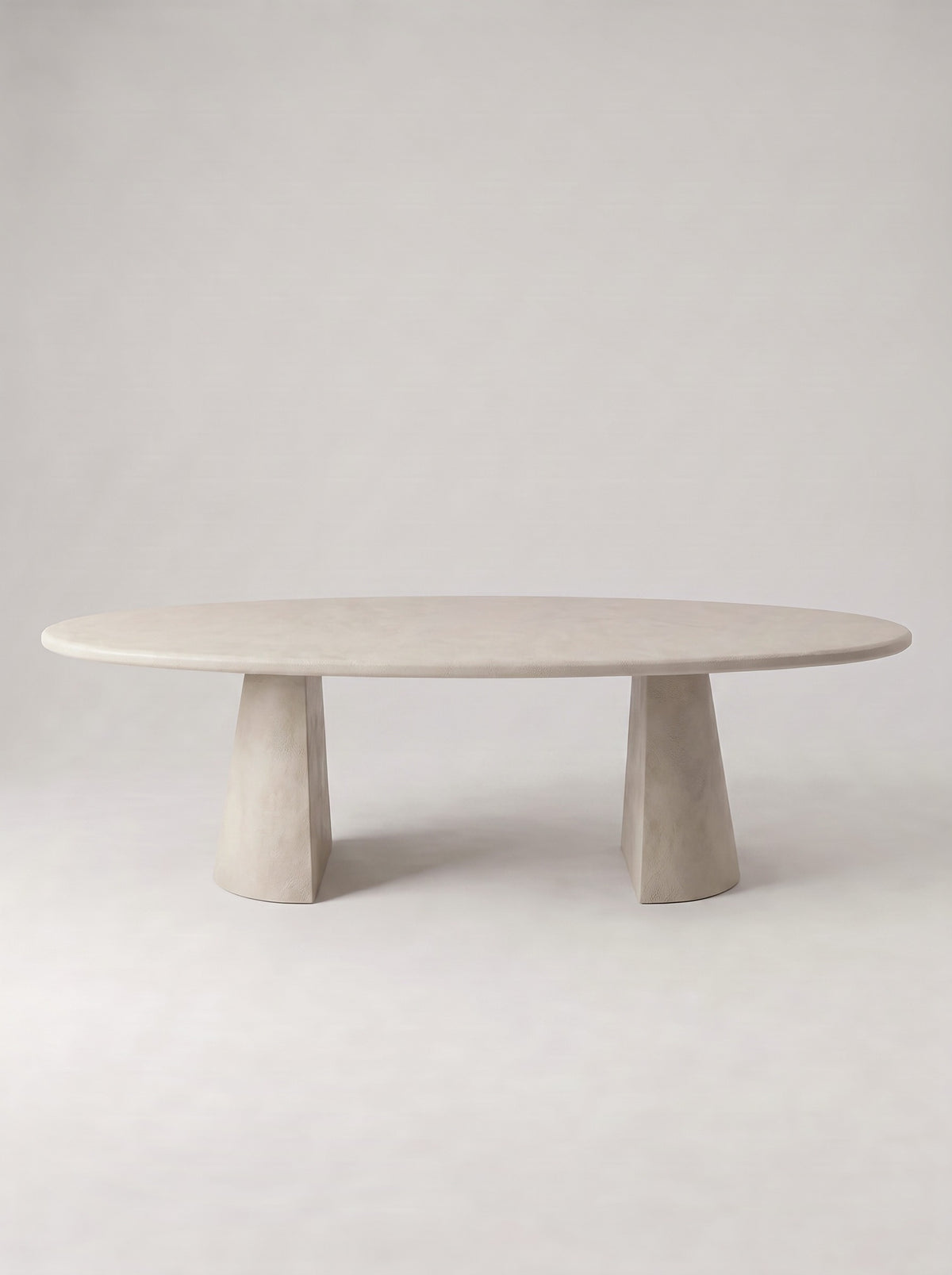Kegel eettafel met ovaal blad in beton ciré op twee conische poten, vooraanzicht