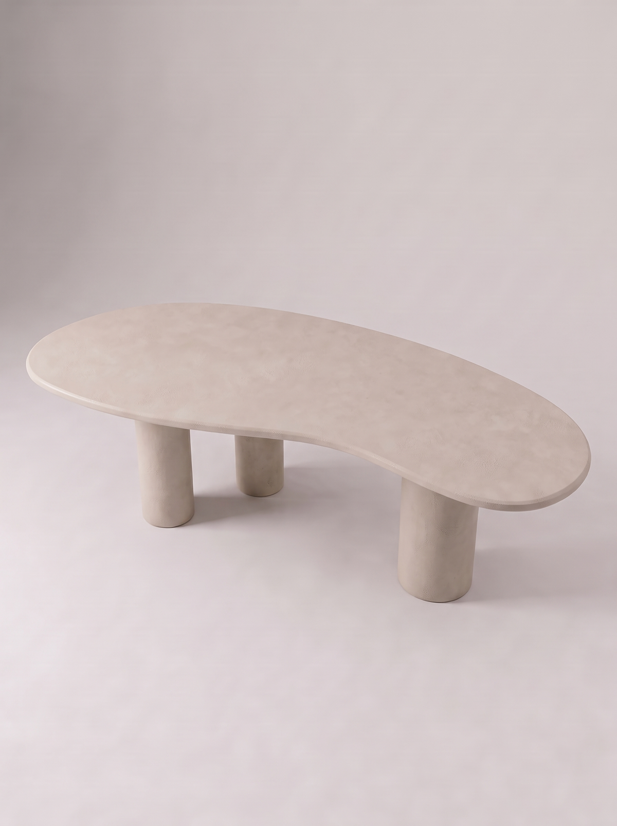 Blad eettafel in beton ciré met organisch bladvormig blad op drie ronde poten